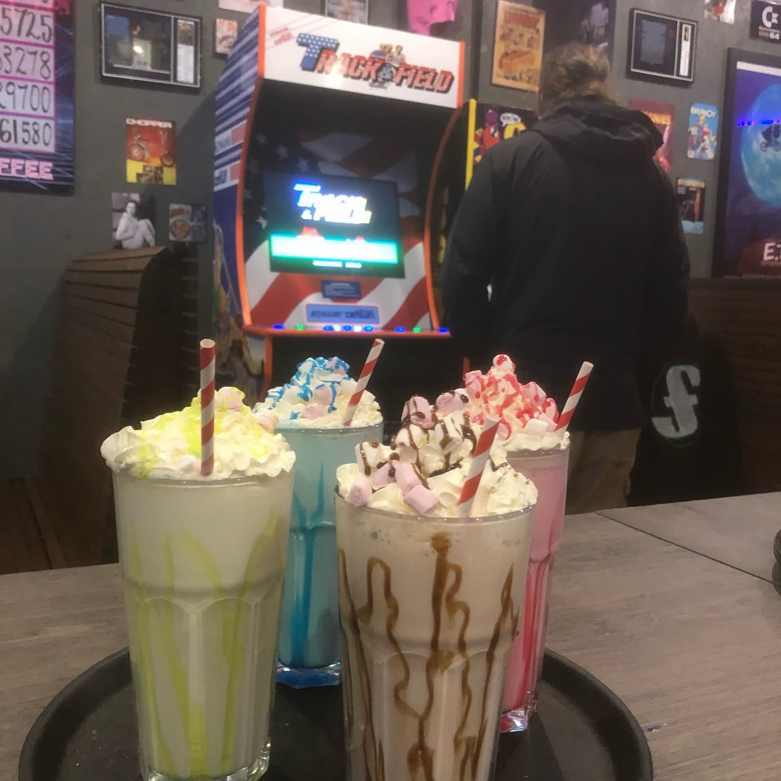 Four retro milkshakes in front of a Track & Field arcade cabinet