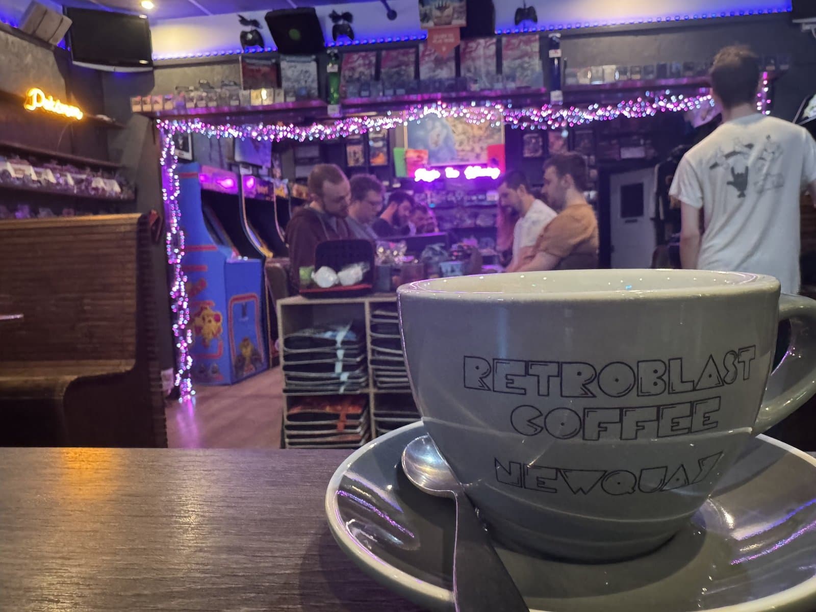 RetroBlast Coffee mug in the foreground with arcade cabinets and a Pinball neon glowing behind
